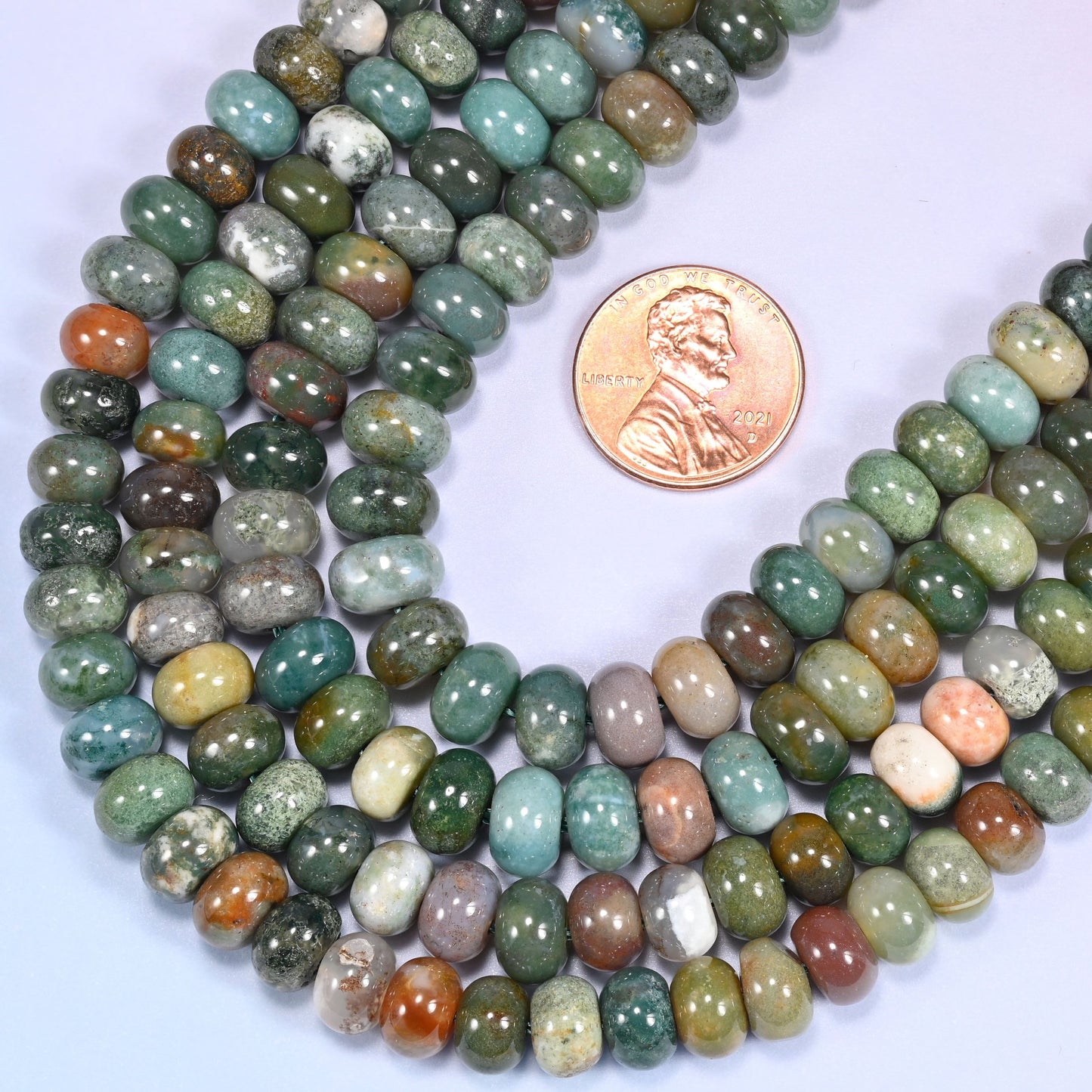 Rows of Indian Agate rondelle beads laid straight on a lavender surface, showing the natural stone color variation.