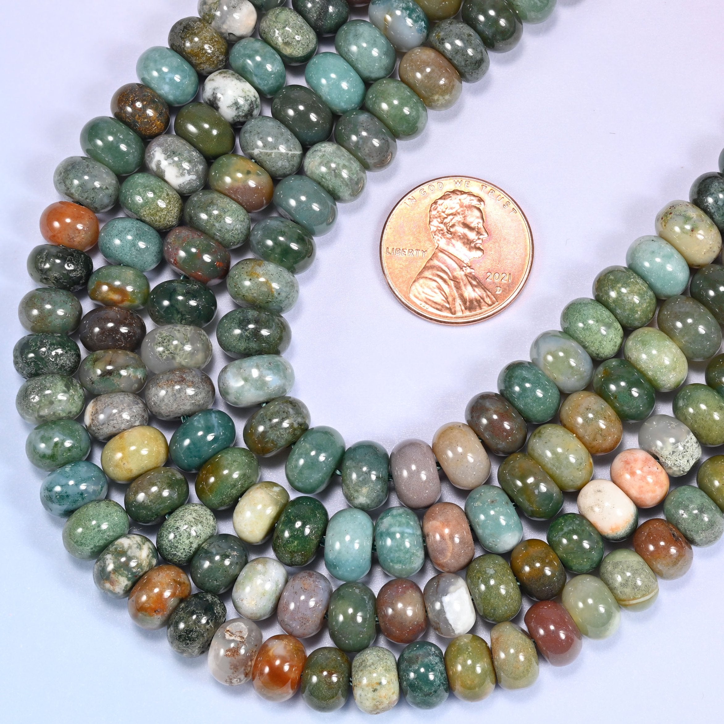 Rows of Indian Agate rondelle beads laid straight on a lavender surface, showing the natural stone color variation.