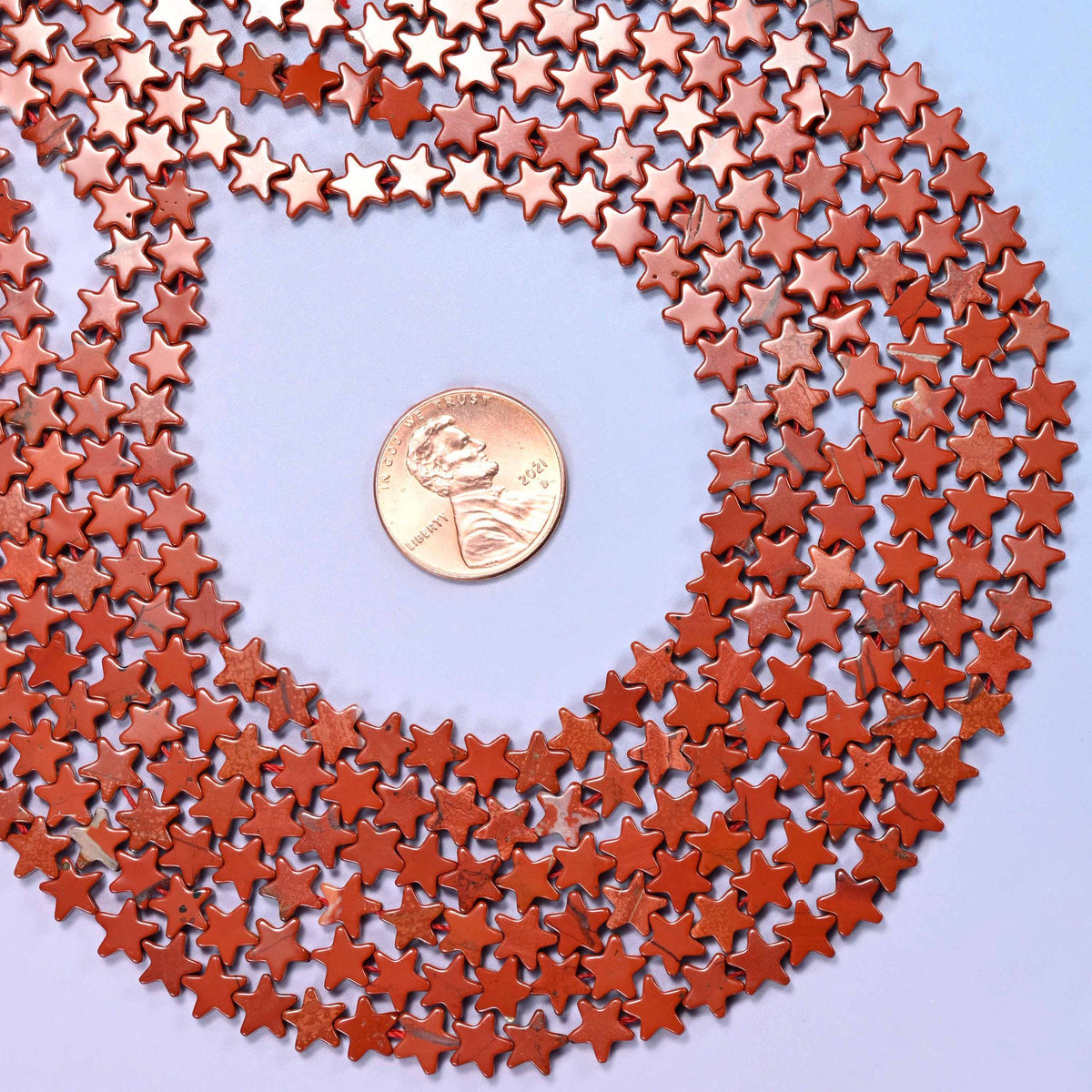Red jasper flat star beads in warm brick and terracotta red, fully opaque with a soft even polish.