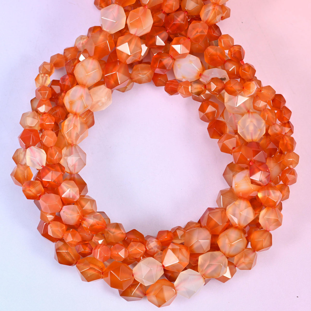 Orange Agate star cut beads coiled in a loop, approximately 38 beads per 10mm strand