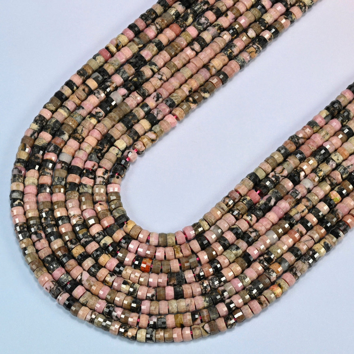 Rhodonite faceted heishi disc beads in several strands curved into a wide U, dusty pink and black stone