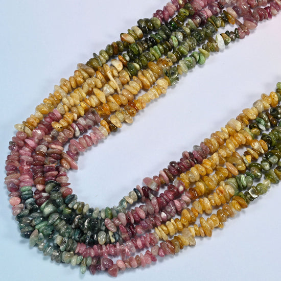 Multicolor tourmaline chip beads in several strands curved into a wide U, raspberry pink, teal green and honey yellow chips