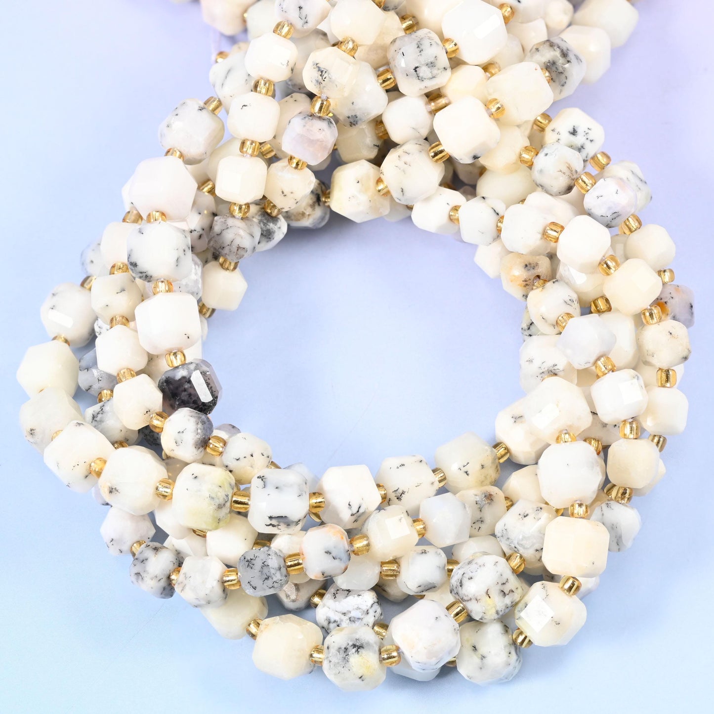 Creamy ivory white flecked with grey and soft dendritic markings, opaque with a gentle waxy glow.