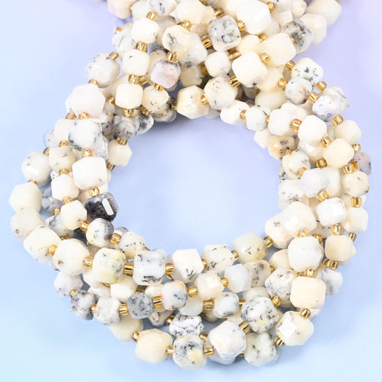 Creamy ivory white flecked with grey and soft dendritic markings, opaque with a gentle waxy glow.