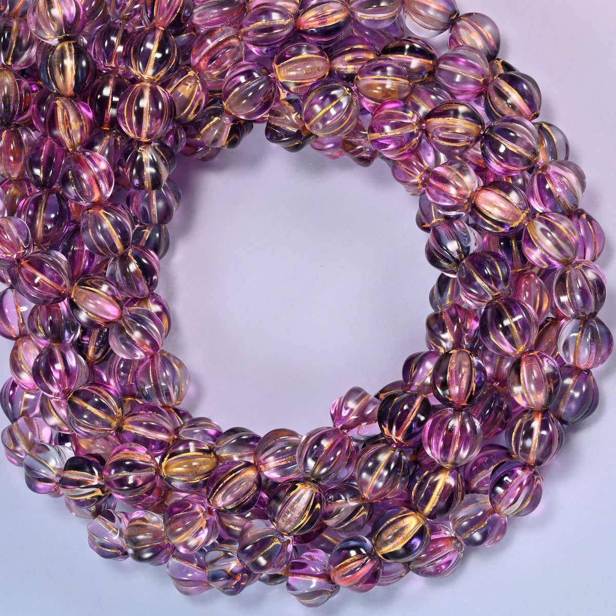 Pink blue gold pumpkin glass beads coiled into a densely packed ring with a small round opening.