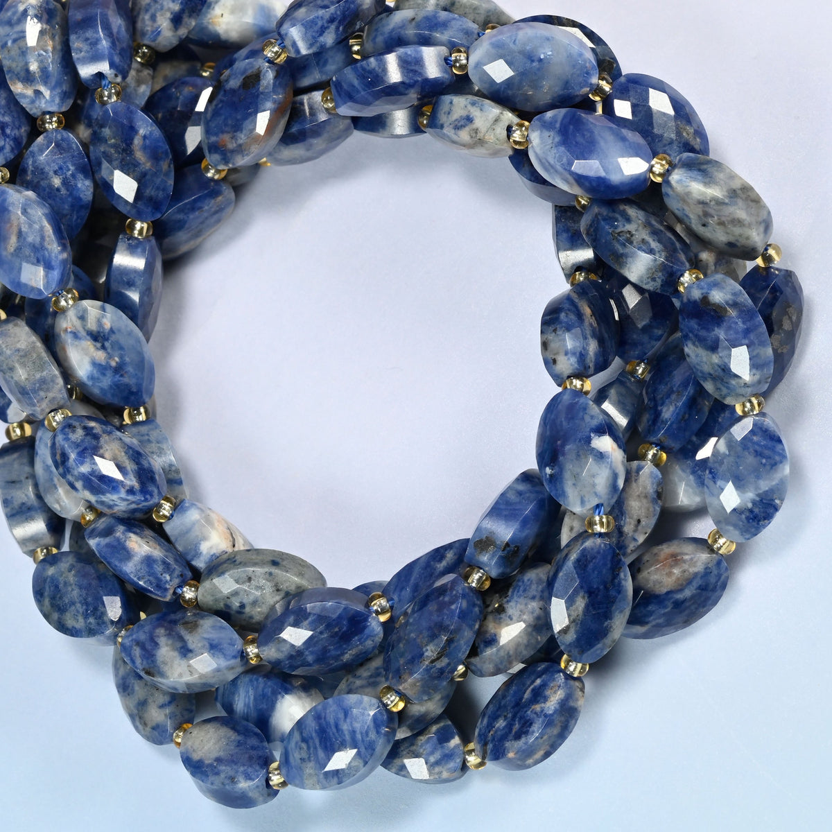 Orange sodalite faceted flat oval beads coiled into overlapping loops, whole strands of deep blue and peach-orange stone