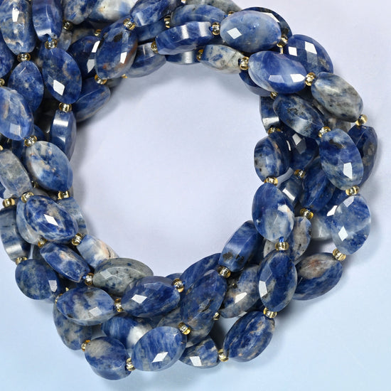 Orange sodalite faceted flat oval beads coiled into overlapping loops, whole strands of deep blue and peach-orange stone