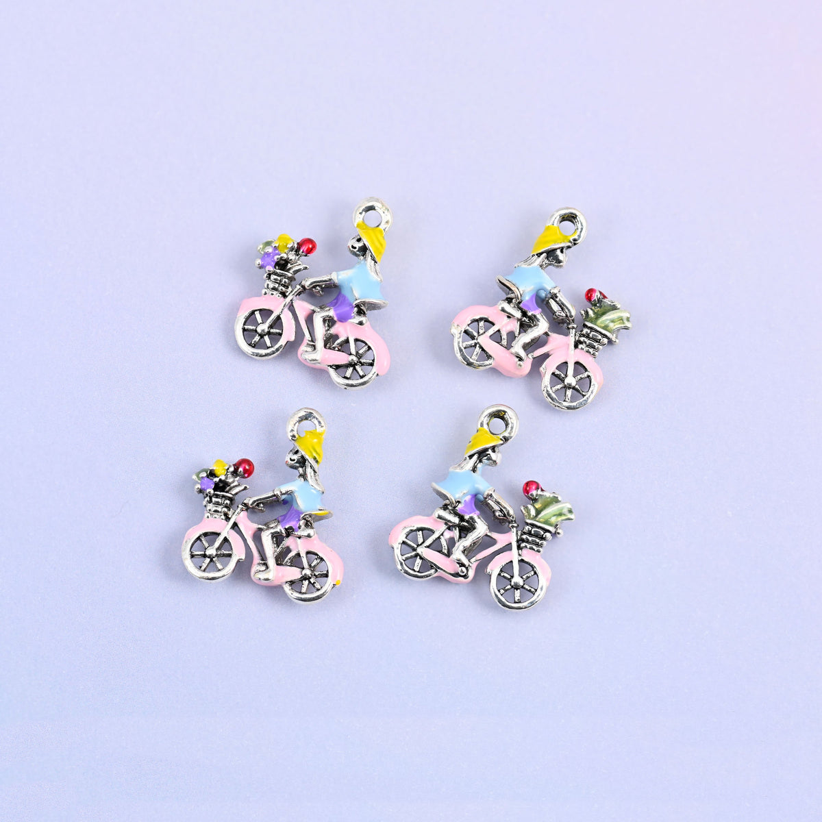 Four bicycle charms grouped, pink frame with a rider in a light blue top and a basket of flowers.
