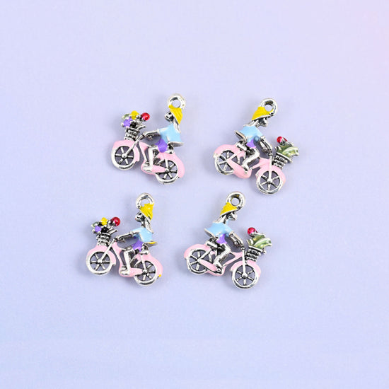Four bicycle charms grouped, pink frame with a rider in a light blue top and a basket of flowers.