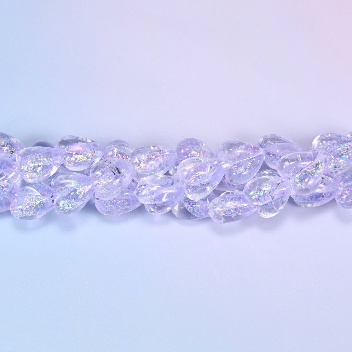 Transparent pale lilac glass hearts with a glittering iridescent shimmer that throws pink and silver flashes