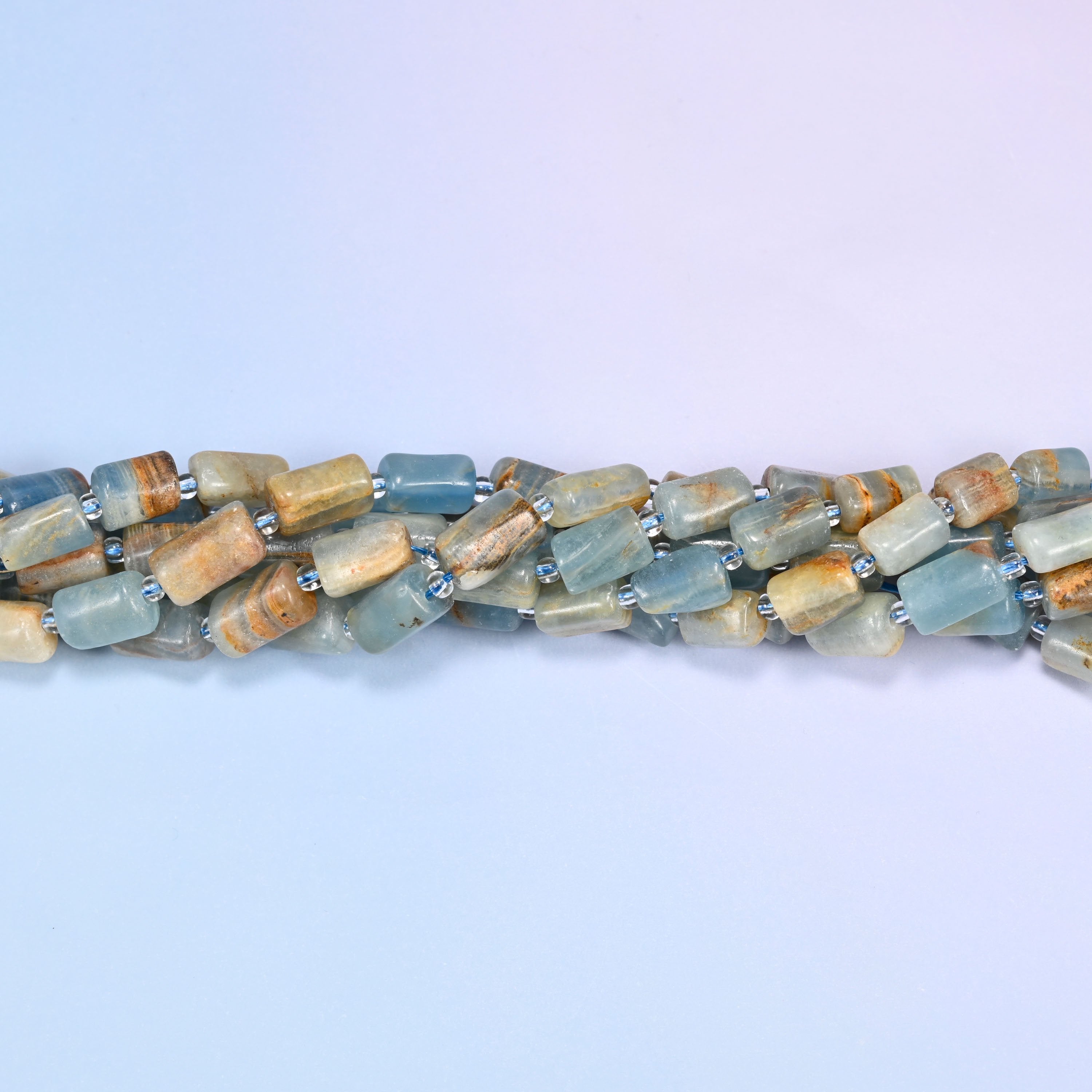 Close-up of coiled Blue Calcite tube beads with clear glass spacers, showing the natural stone texture and color variation.