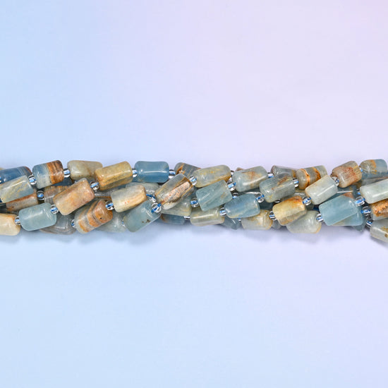 Close-up of coiled Blue Calcite tube beads with clear glass spacers, showing the natural stone texture and color variation.