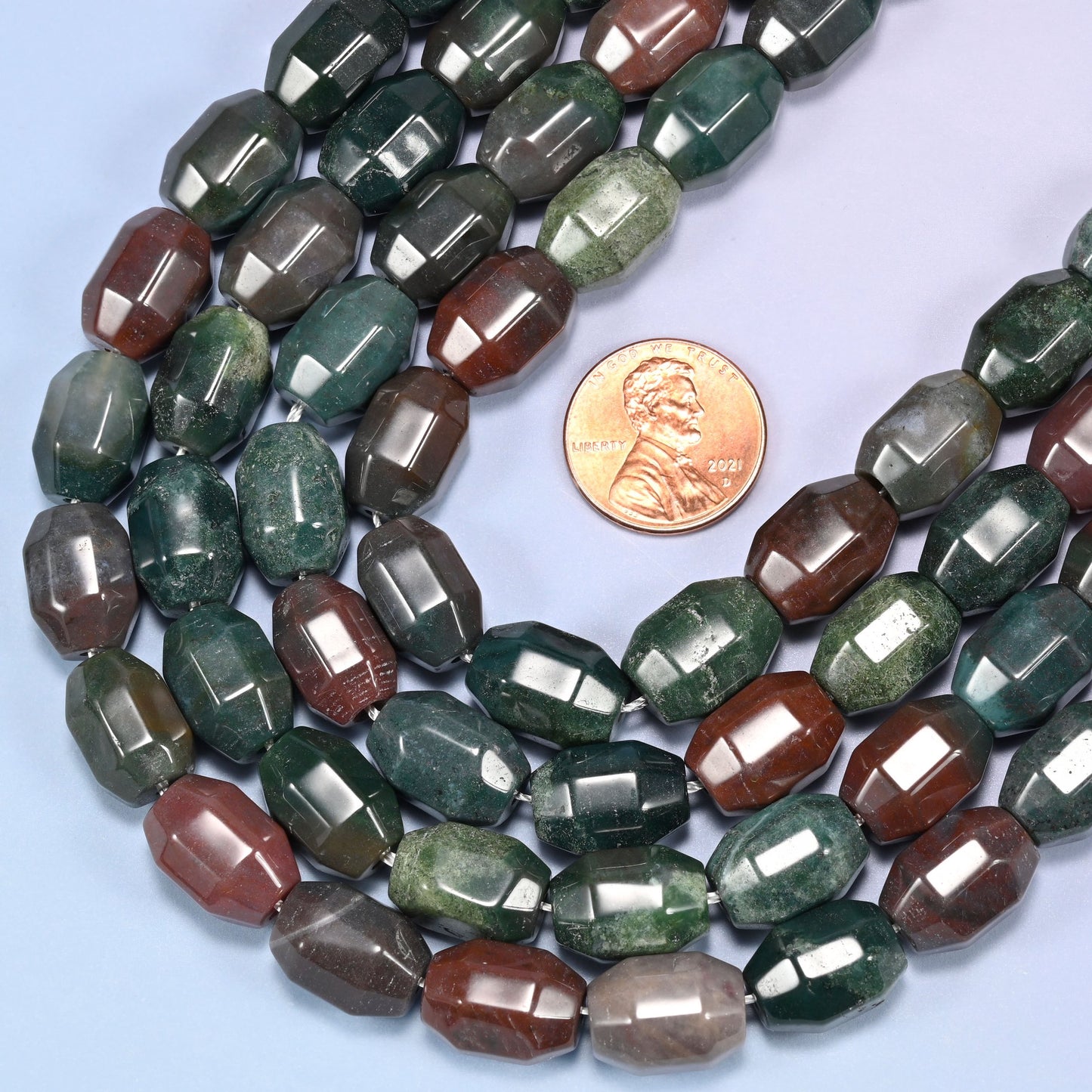 Close-up of a dense circular coil of Indian Agate faceted barrel beads, showing the octagonal facet cuts.