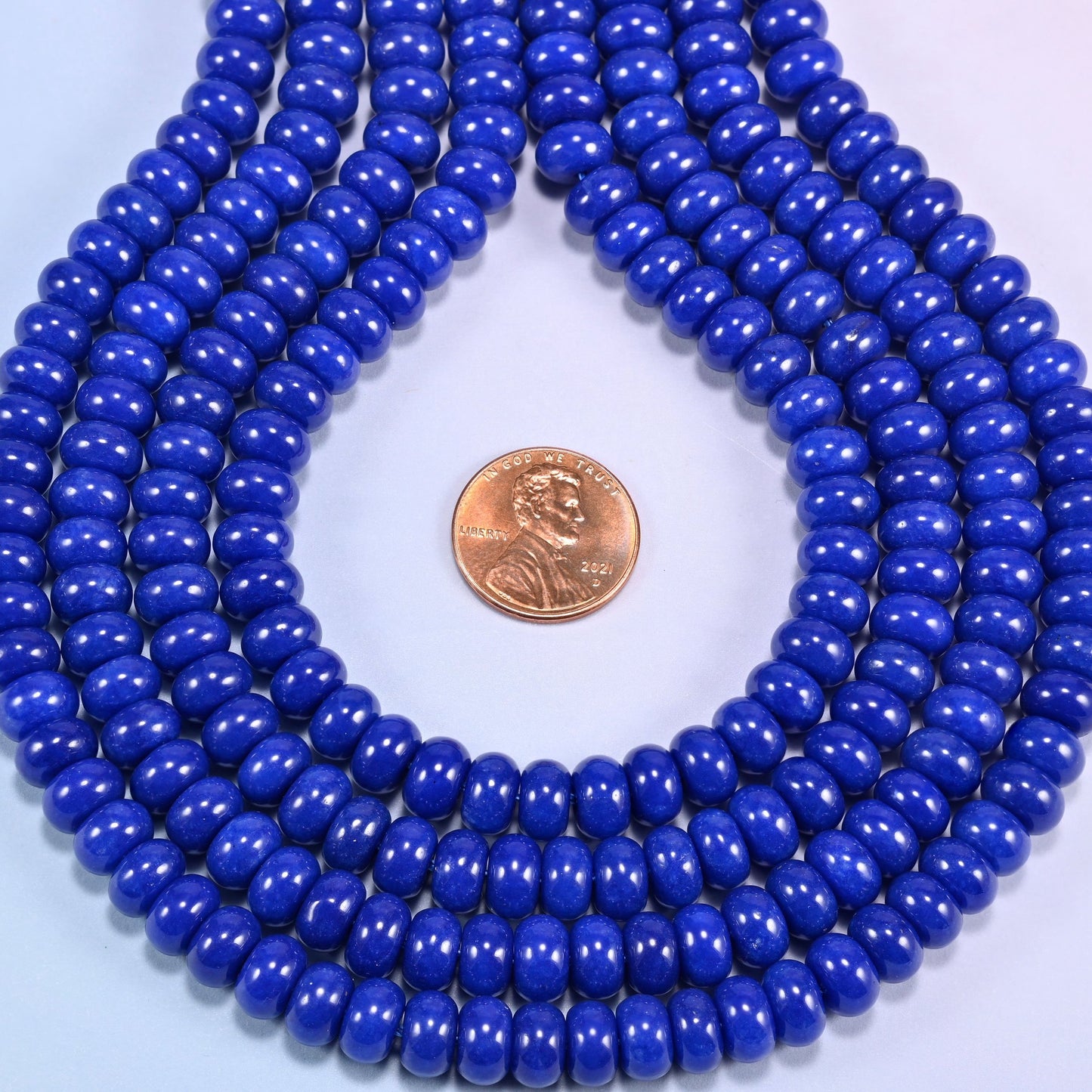 Dark Blue dyed jade gemstone rondelle beads in a teardrop coil, deep blue discs stacked close together