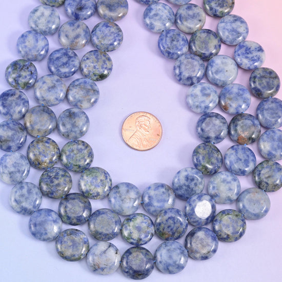 Close crop of polished blue spot jasper coins catching soft light across their faces