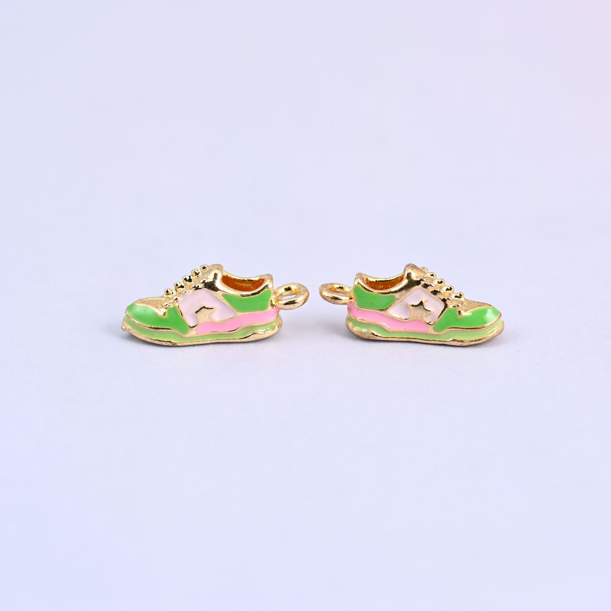 Two green sneaker charms side by side with pink stripes and gold plated laces.