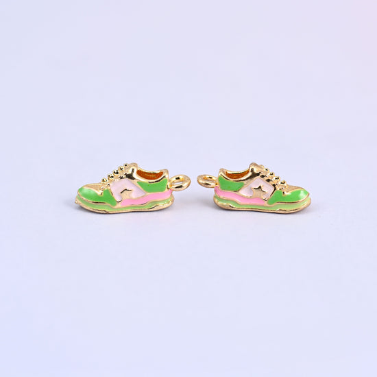 Two green sneaker charms side by side with pink stripes and gold plated laces.