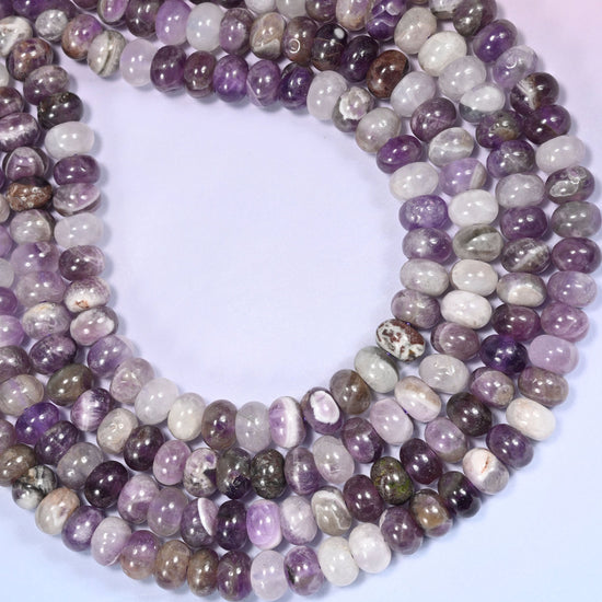 Circular coil of Amethyst bead strands on a lavender background with a penny in the center for size comparison.