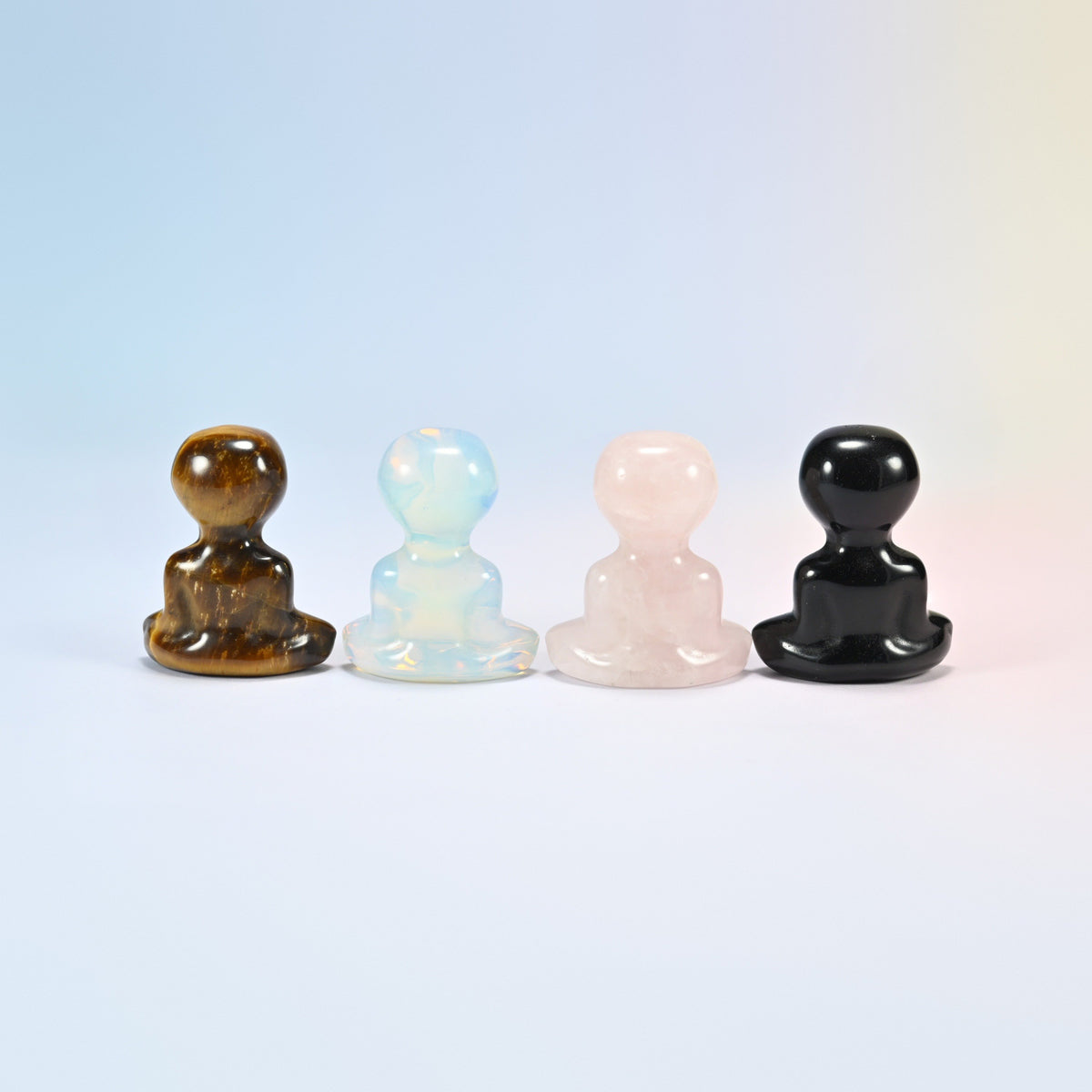 Back view of four yoga alien carvings in tiger eye, opalite, rose quartz and black obsidian