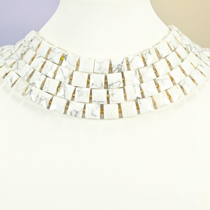 White howlite faceted flat square strands arranged as a layered collar on a white display bust, white beads across the neck