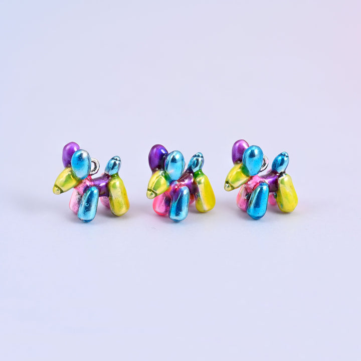 Three balloon dog charms in a row, metallic enamel in blue, purple, pink and yellow on 18K white gold plated brass.