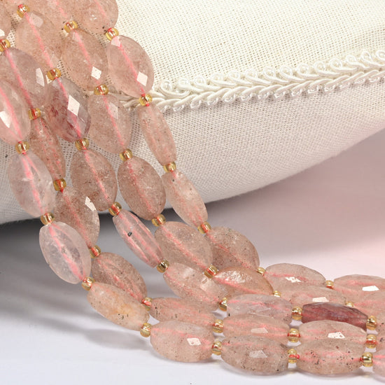 Strawberry quartz faceted flat oval beads 9x14mm with small gold seed bead spacers, several strands draped over a white cushion