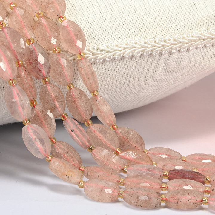 Strawberry quartz faceted flat oval beads 9x14mm with small gold seed bead spacers, several strands draped over a white cushion