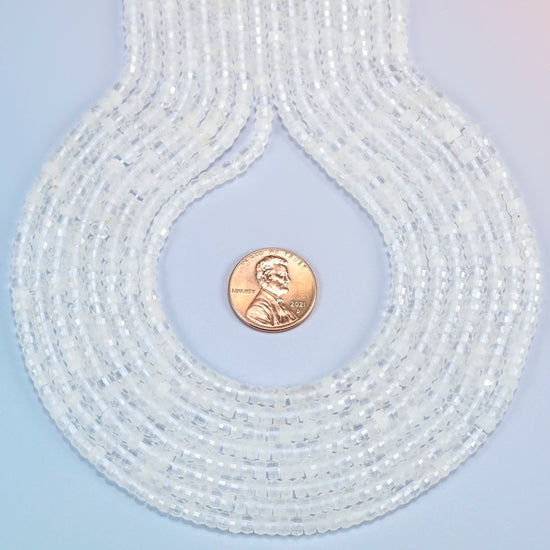 Clear quartz faceted heishi disc strands formed into a teardrop loop around a US penny for scale