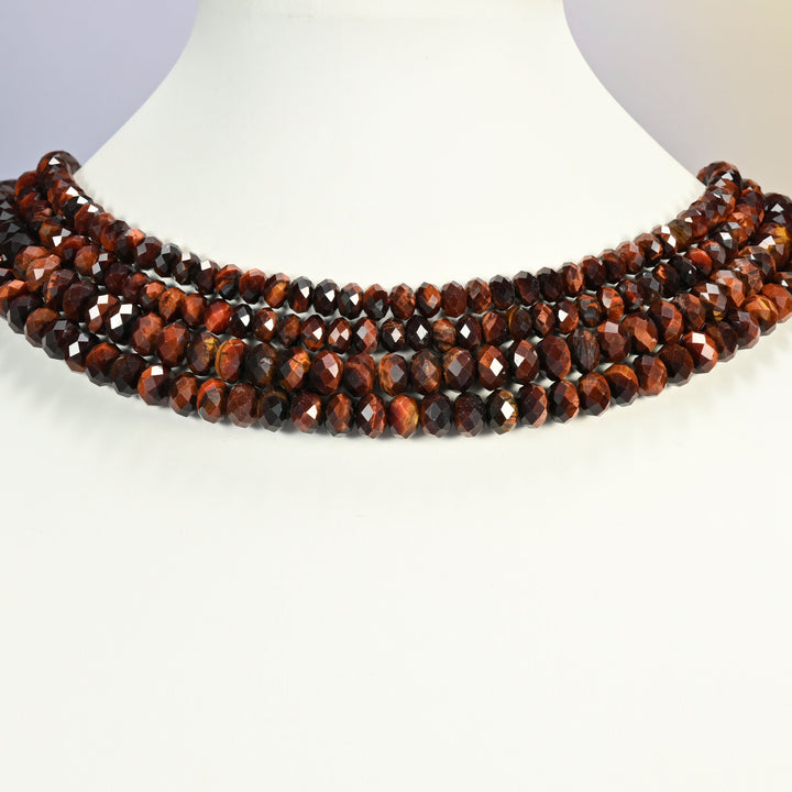 Red tiger eye beads shown on a white neck display bust, the faceted rondelle strands sitting in even rows against the curve of the neck