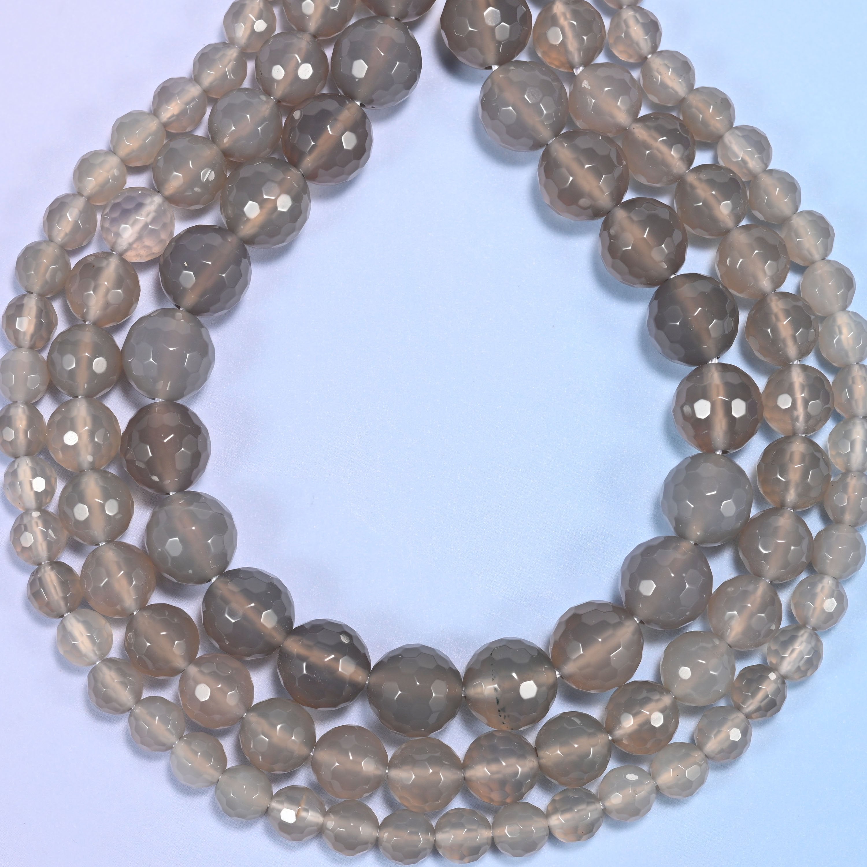 Gray agate faceted round beads photographed at an angle to show natural luster.