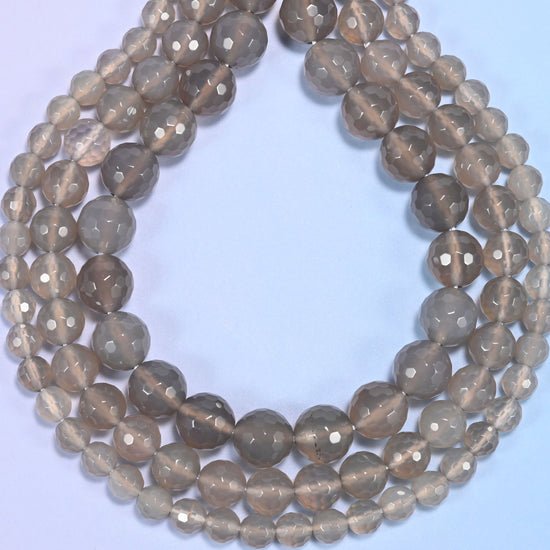 Gray agate faceted round beads photographed at an angle to show natural luster.