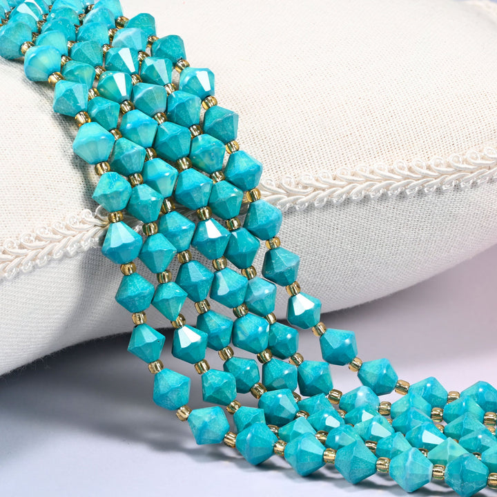 Dyed dark blue howlite faceted bicone beads over a white cushion, deep blue green with gold spacers.