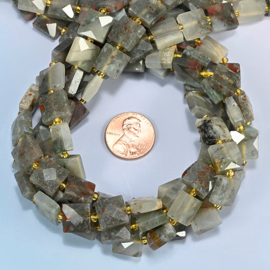 Natural African bloodstone faceted flat square beads 10x10mm coiled in a loop around a US penny for scale, close-up of the faceted flat square shape