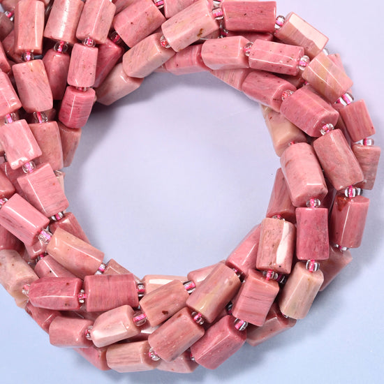 Pink Rhodonite faceted tube beads coiled into a ring, colour running from deeper rose to near cream from bead to bead