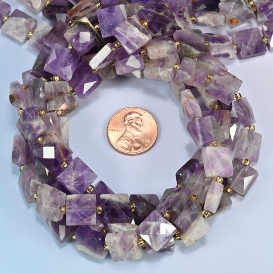 Natural amethyst faceted flat square beads 10x10mm coiled in a loop around a US penny for scale, close-up of the faceted flat square shape