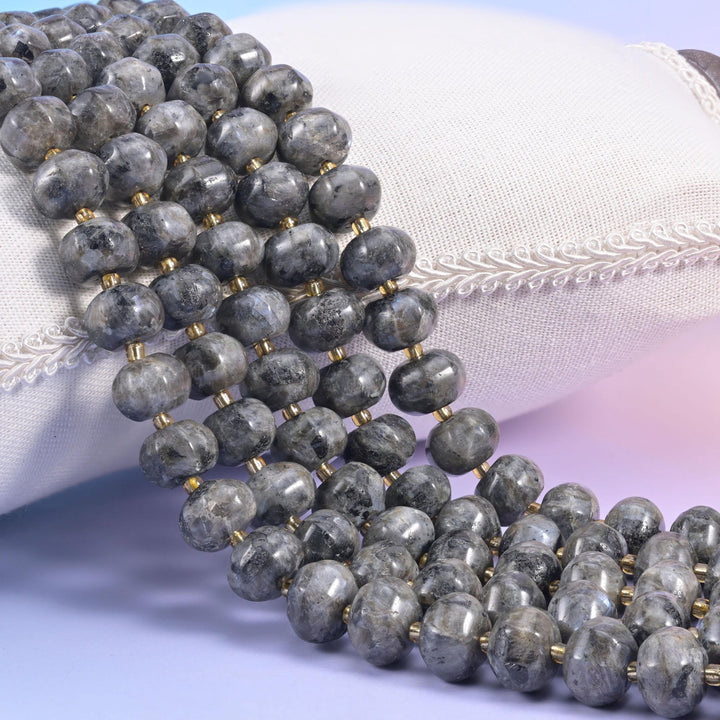 Black labradorite pumpkin rondelle strands on a cream cushion, ribbed grey beads with gold spacers