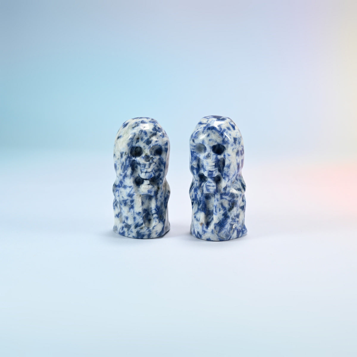 Two natural blue spot jasper hooded skull carvings, white with navy blue spots