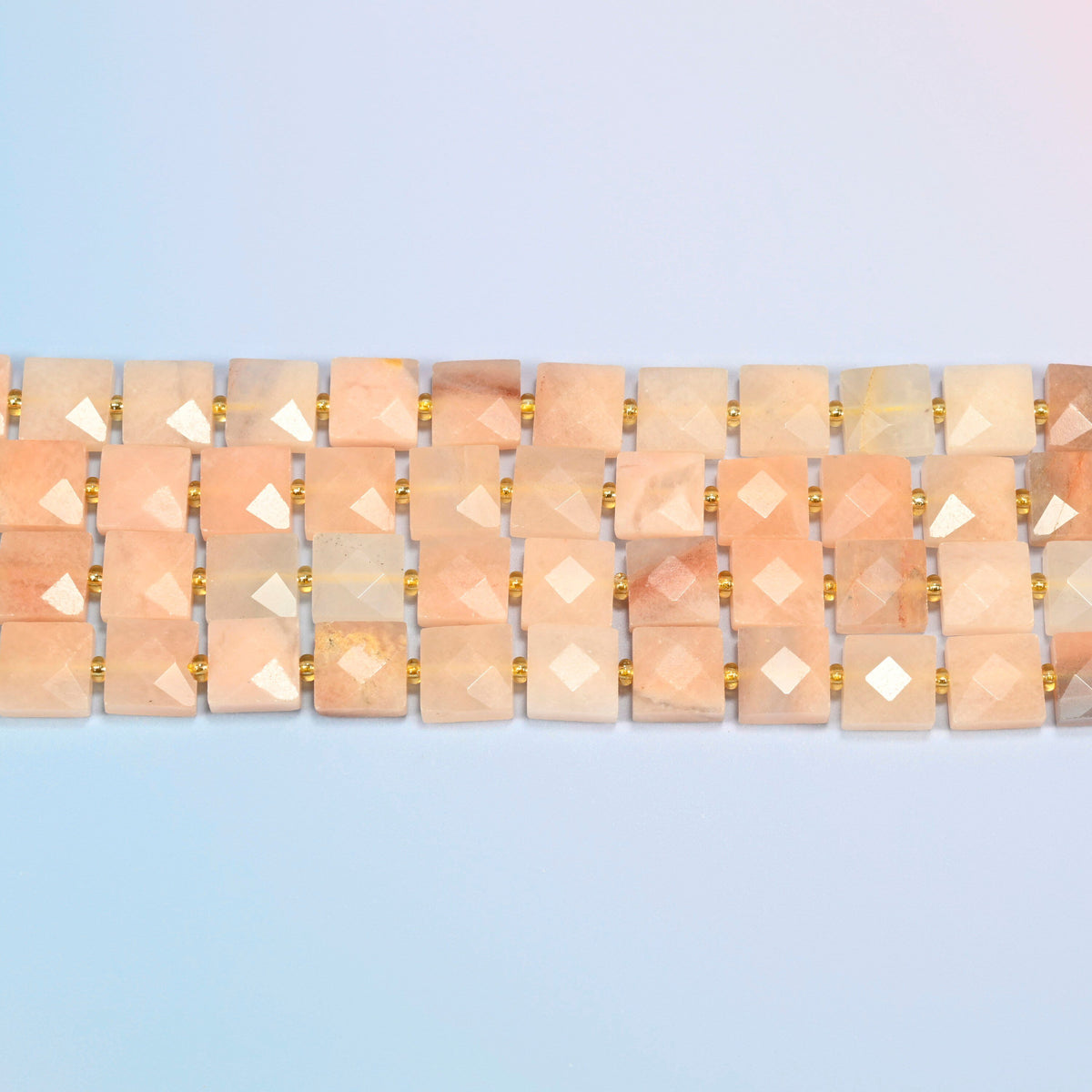 Several strands of natural pink aventurine faceted flat square beads laid in straight rows