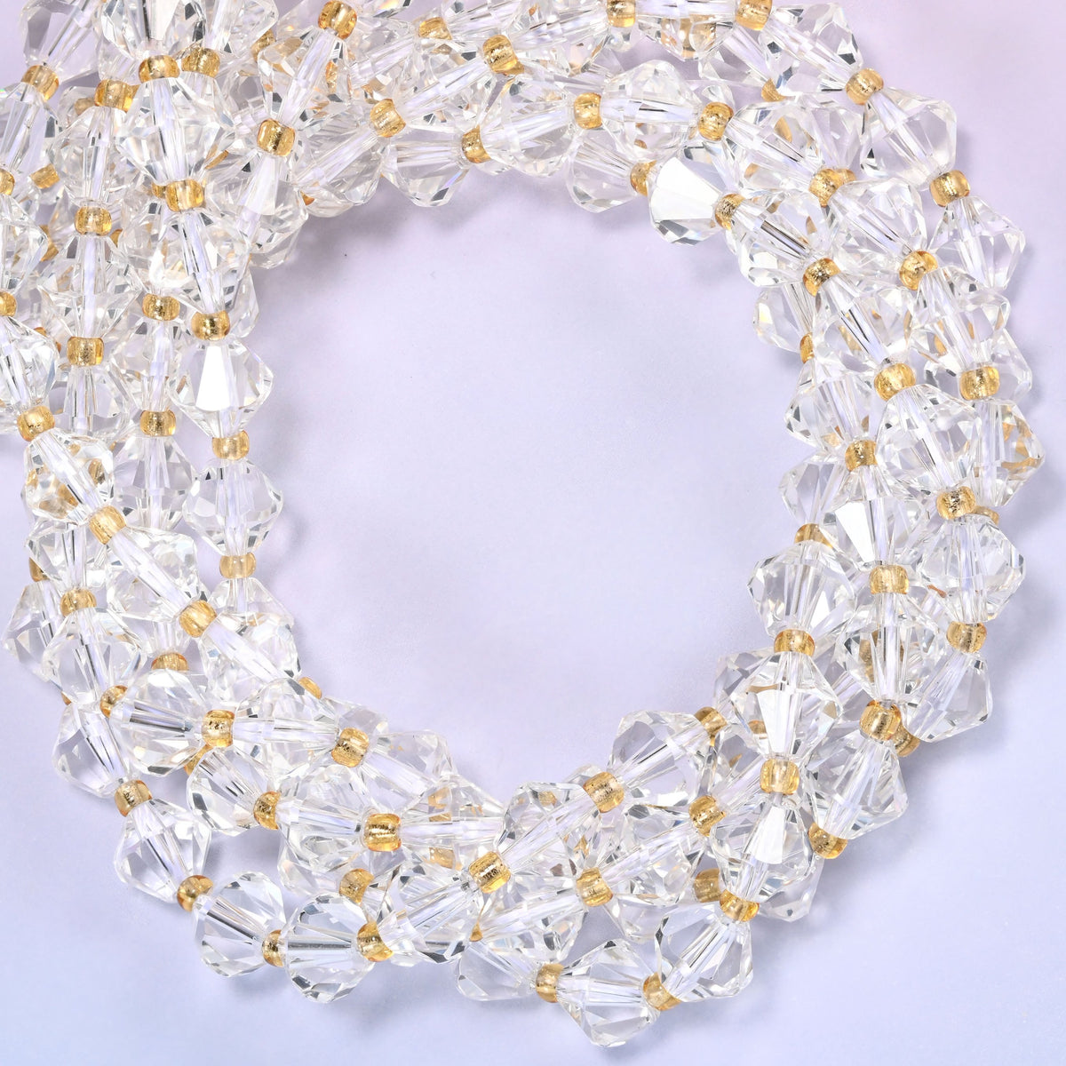 8mm Clear Quartz faceted bicone beads coiled tightly into overlapping loops on a light lavender background.