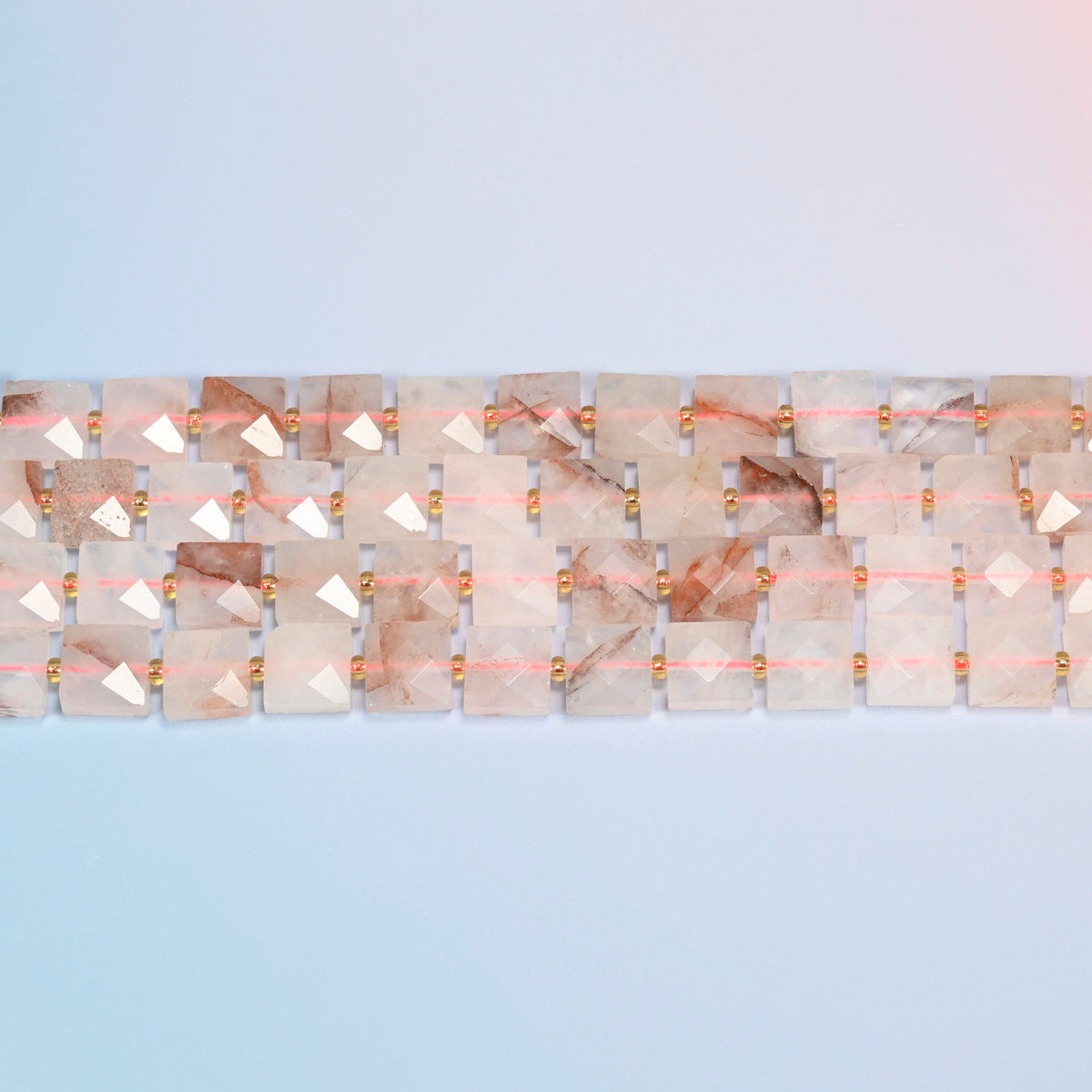 Several strands of natural red hematoid quartz faceted flat square beads laid in straight rows