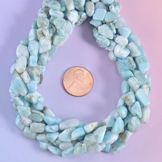 Open loop of larimar nuggets around a penny, the pale blue reading almost white in places