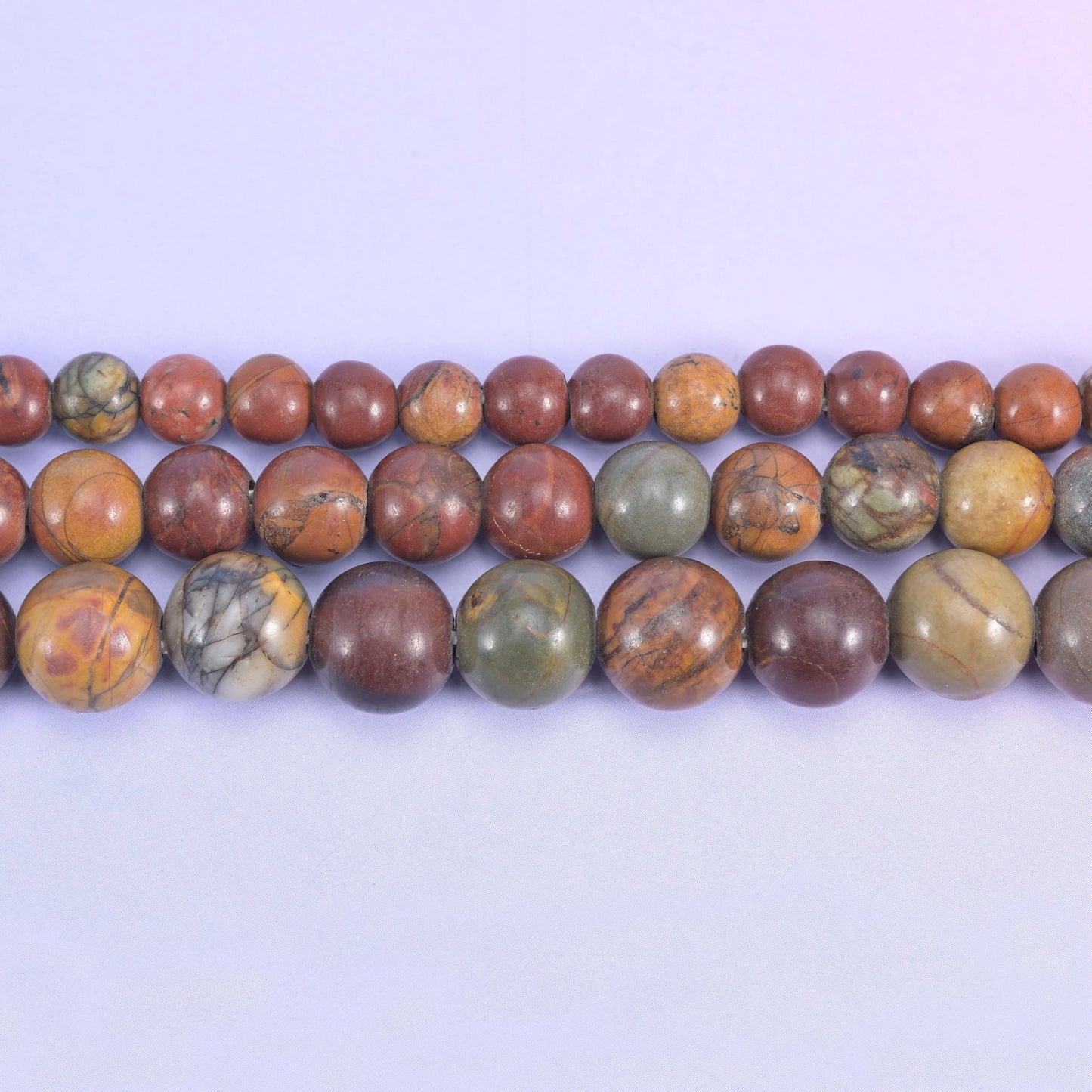 Brick red and terracotta rounds marbled with tan, cream and olive-grey, closer to a desert jasper than a plain red stone — and drilled 2.0-2.5mm so leather, thick cord and elastic go straight through.