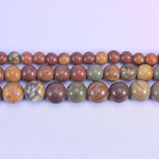 Brick red and terracotta rounds marbled with tan, cream and olive-grey, closer to a desert jasper than a plain red stone — and drilled 2.0-2.5mm so leather, thick cord and elastic go straight through.