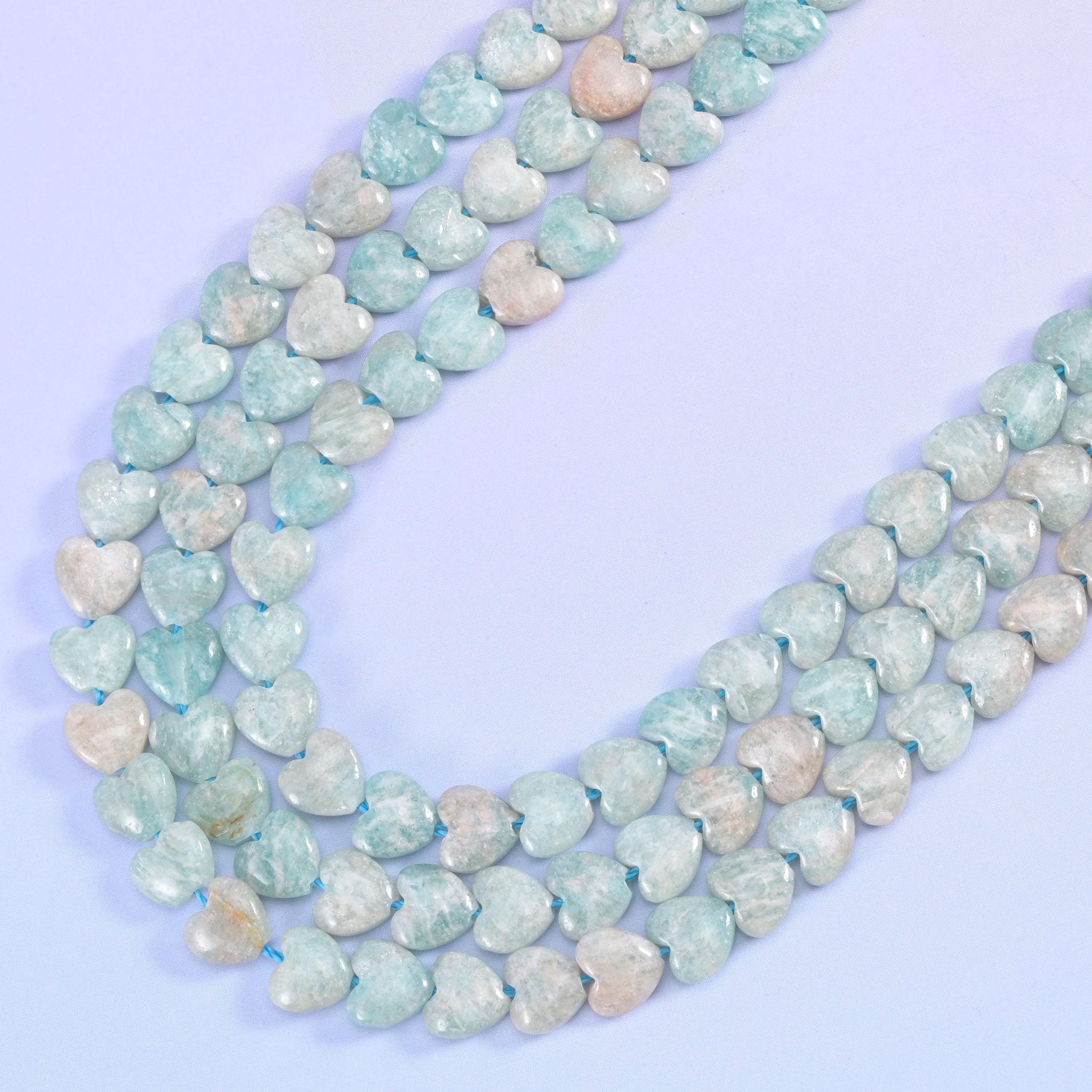 Blue Amazonite heart strands curving in a wide U on a lilac background