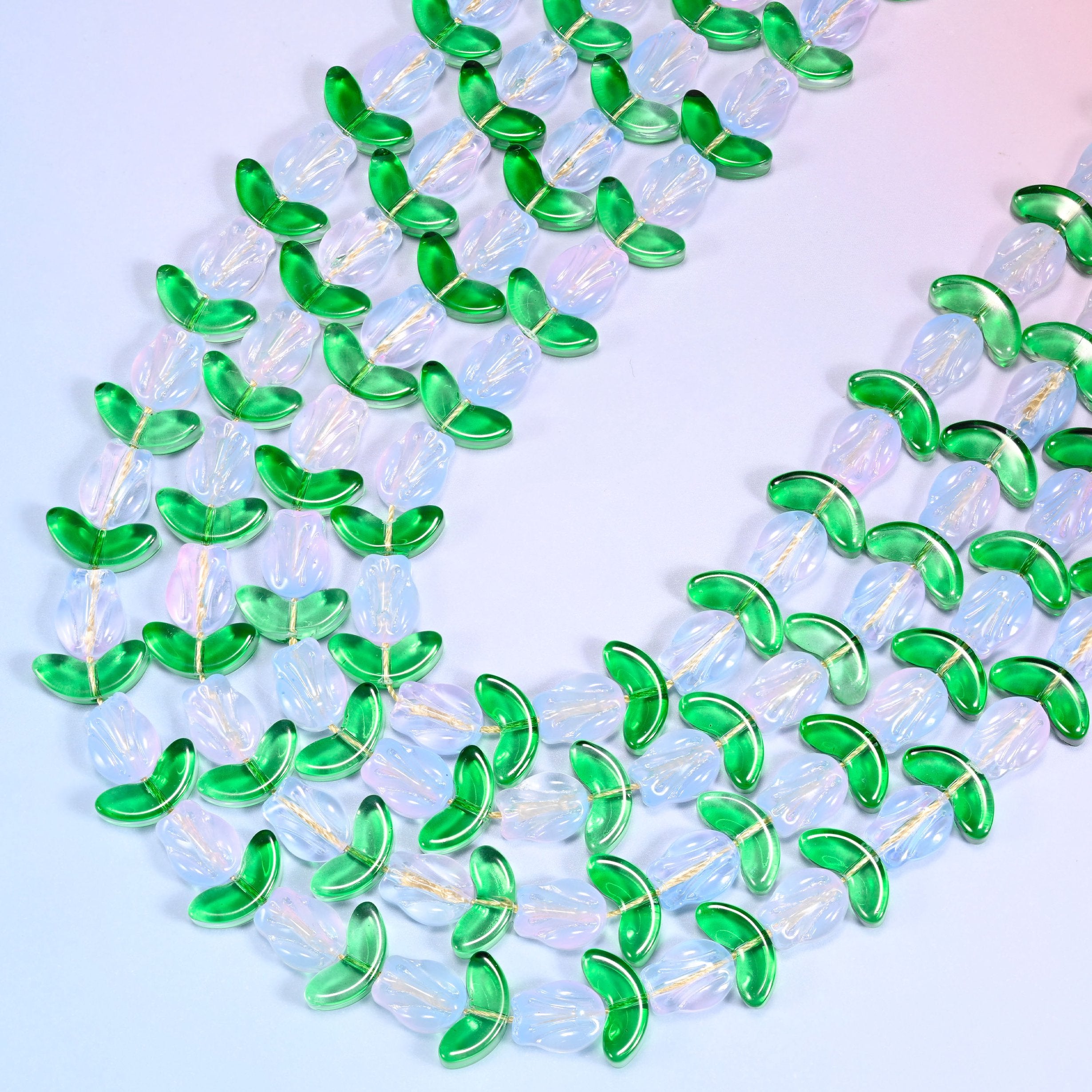 Close-up of a dense circular coil of white tulip and green leaf glass beads on a lavender background.