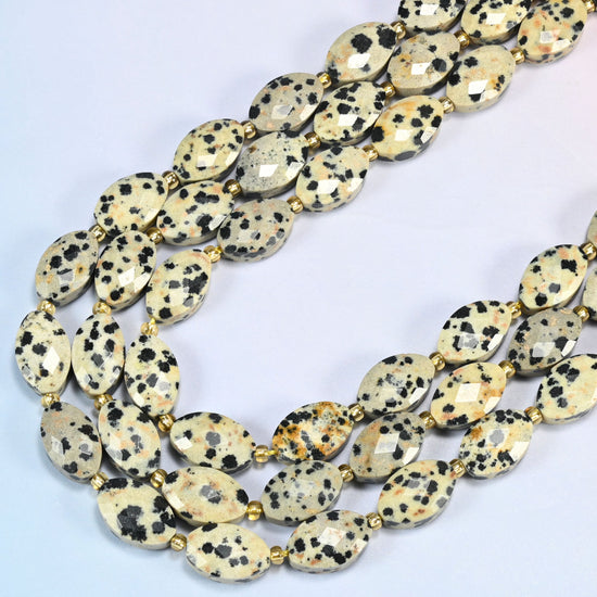 Dalmatian jasper faceted flat oval beads in several strands curved into a wide U, cream with black spots