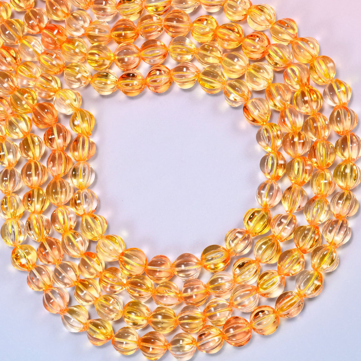 Yellow gold pumpkin glass beads coiled into a ring, shown with a US penny in the open center for scale.