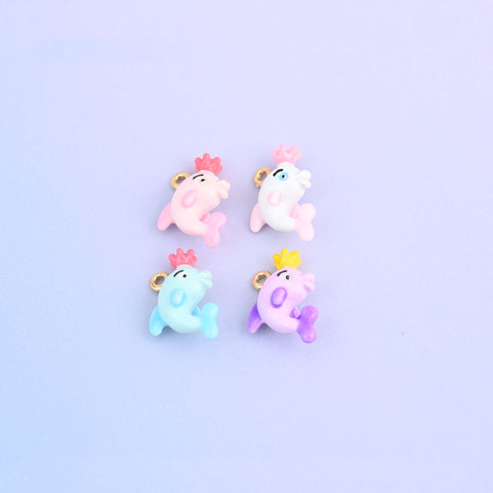 Four dolphin charms with crowns laid out together, showing the moulded tail and side fin on each.