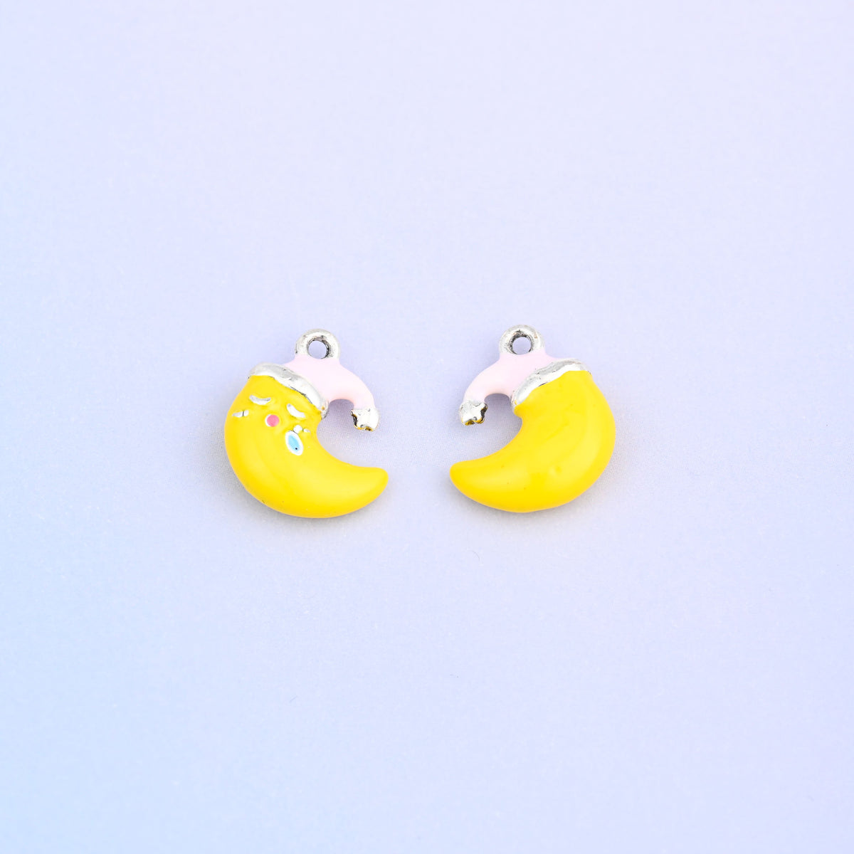 Yellow crescent moon charm in a light pink Santa hat, front and back.