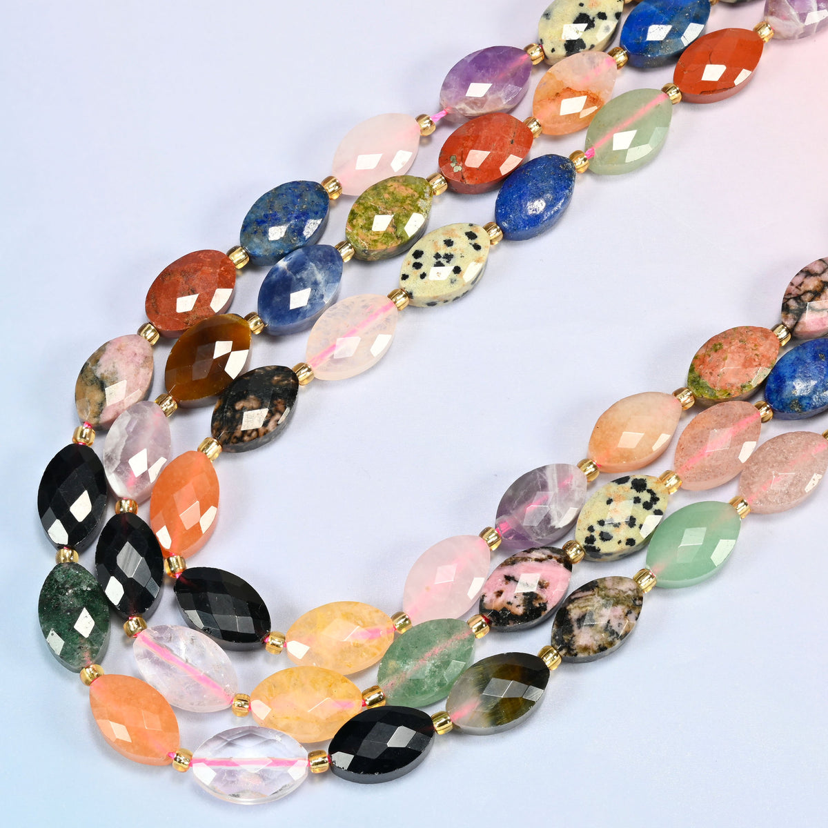 Assorted gemstone faceted flat oval beads in several strands curved into a wide U, colorful mixed stones